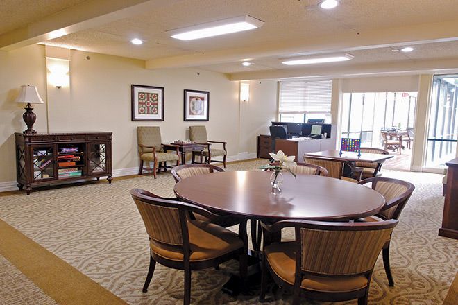 A well-lit dining area with a large table surrounded by chairs, featuring artwork on the walls.