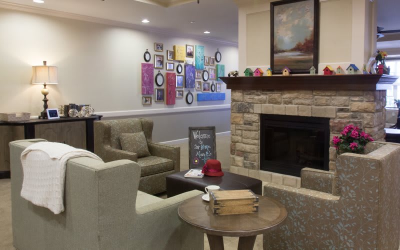 A cozy living room with a fireplace, comfortable seating, and colorful artwork on the walls.