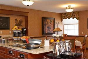 A cozy kitchen setup with a breakfast buffet on the countertop, featuring various food items and a coffee station.