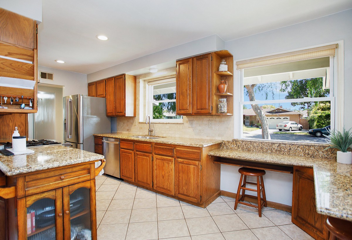 Spacious kitchen with wooden cabinets and granite countertops, featuring stainless steel appliances and a bar seating area.