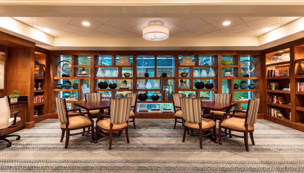 A well-furnished dining area with elegant chairs and tables, surrounded by decorative shelves and ambient lighting.
