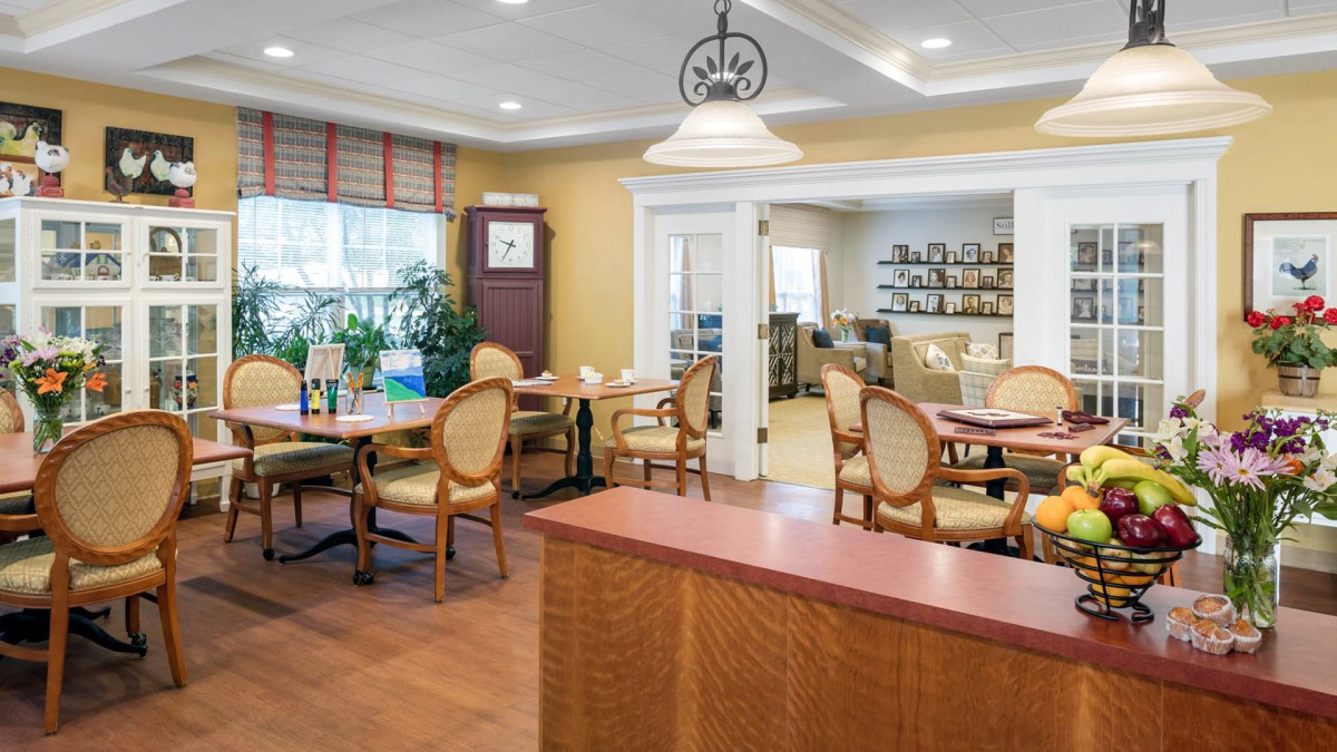 A cozy dining room with neatly arranged tables and chairs, featuring warm lighting and elegant decor.