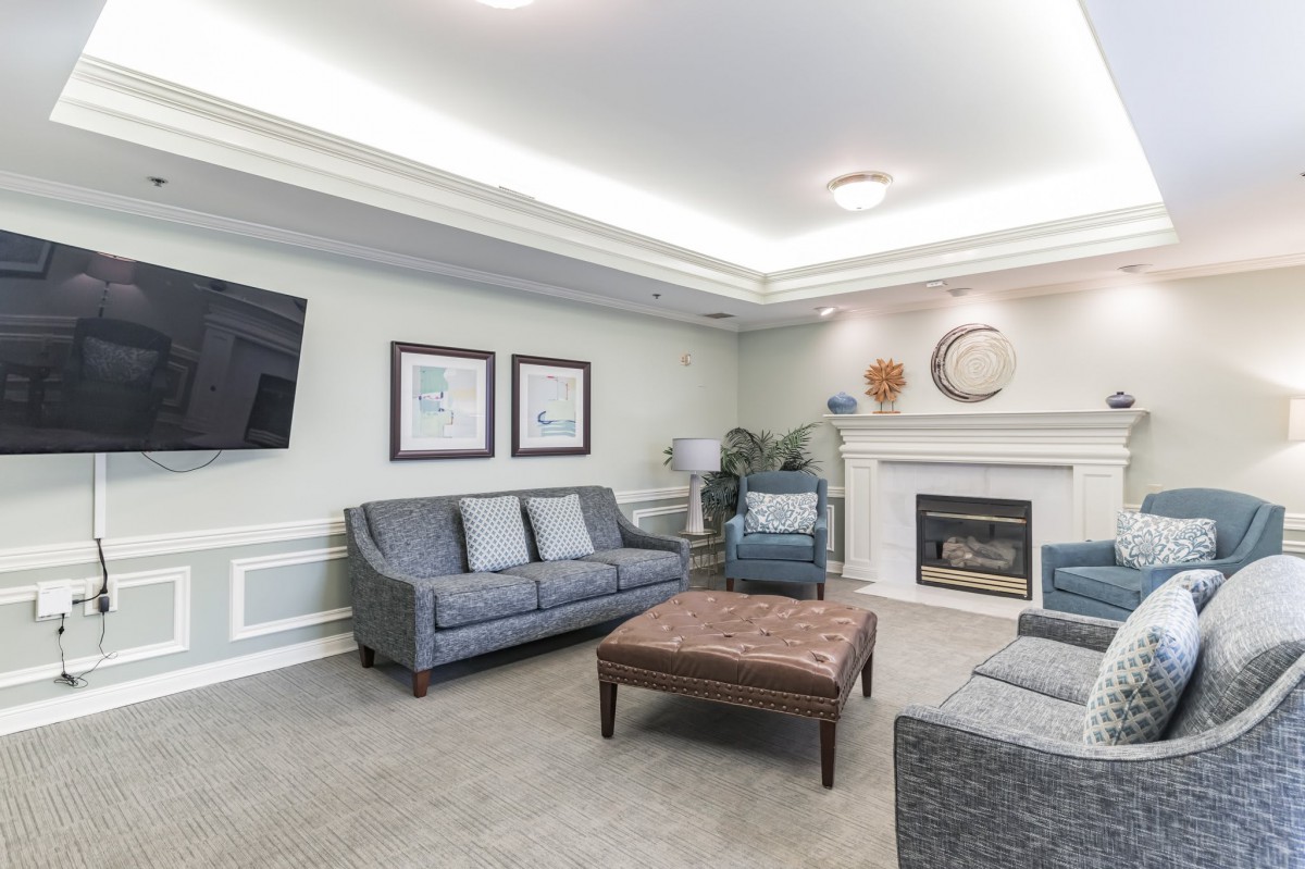 A modern living room featuring comfortable sofas, a wall-mounted TV, and a cozy fireplace.