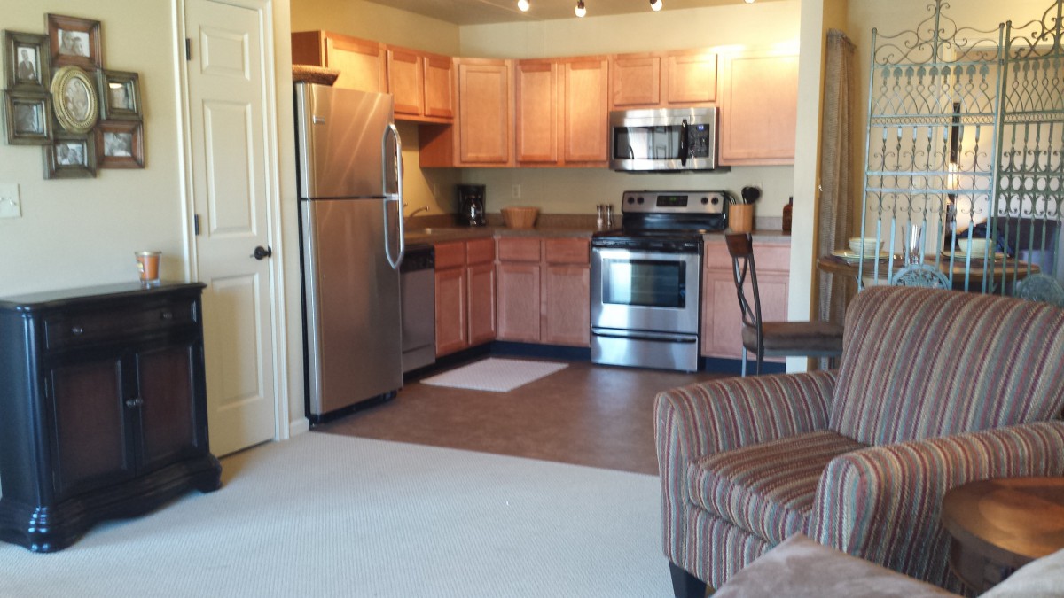 A modern apartment kitchen with stainless steel appliances and wooden cabinets.