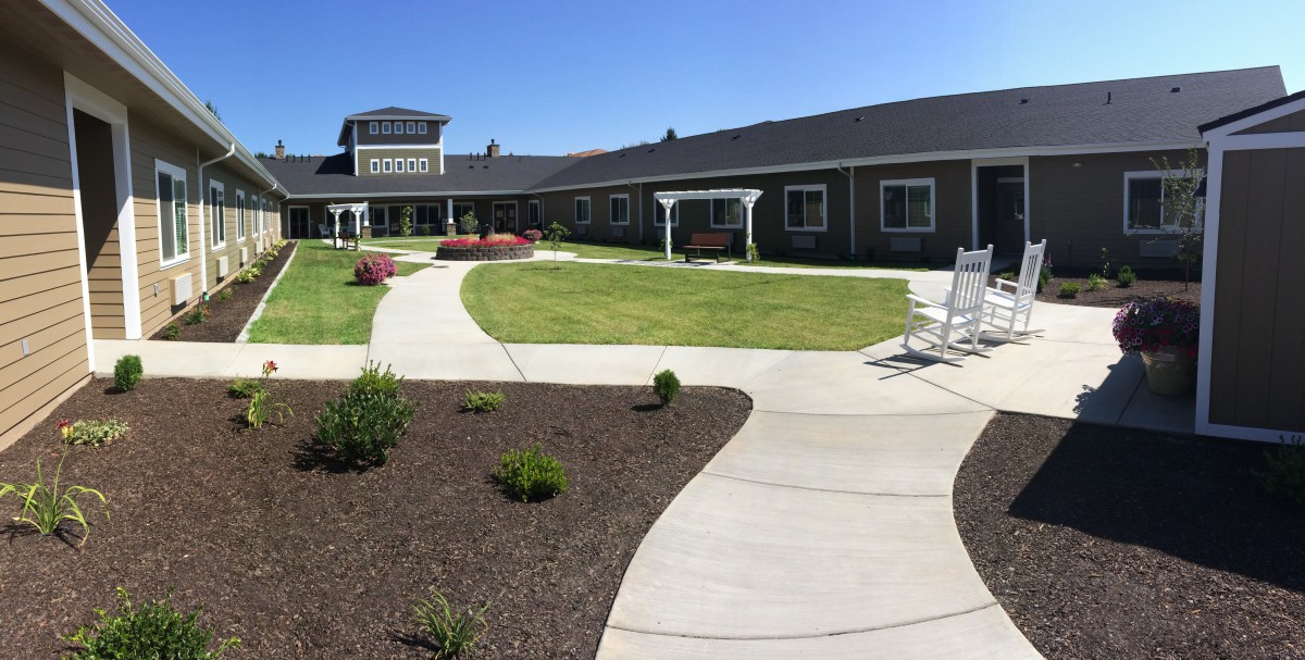 A beautifully landscaped garden with walkways in front of a large building under a clear blue sky.