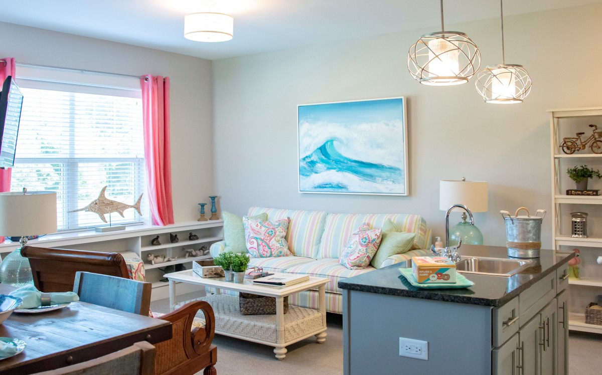 A bright and cozy living room with a sofa, coffee table, and ocean-themed artwork.