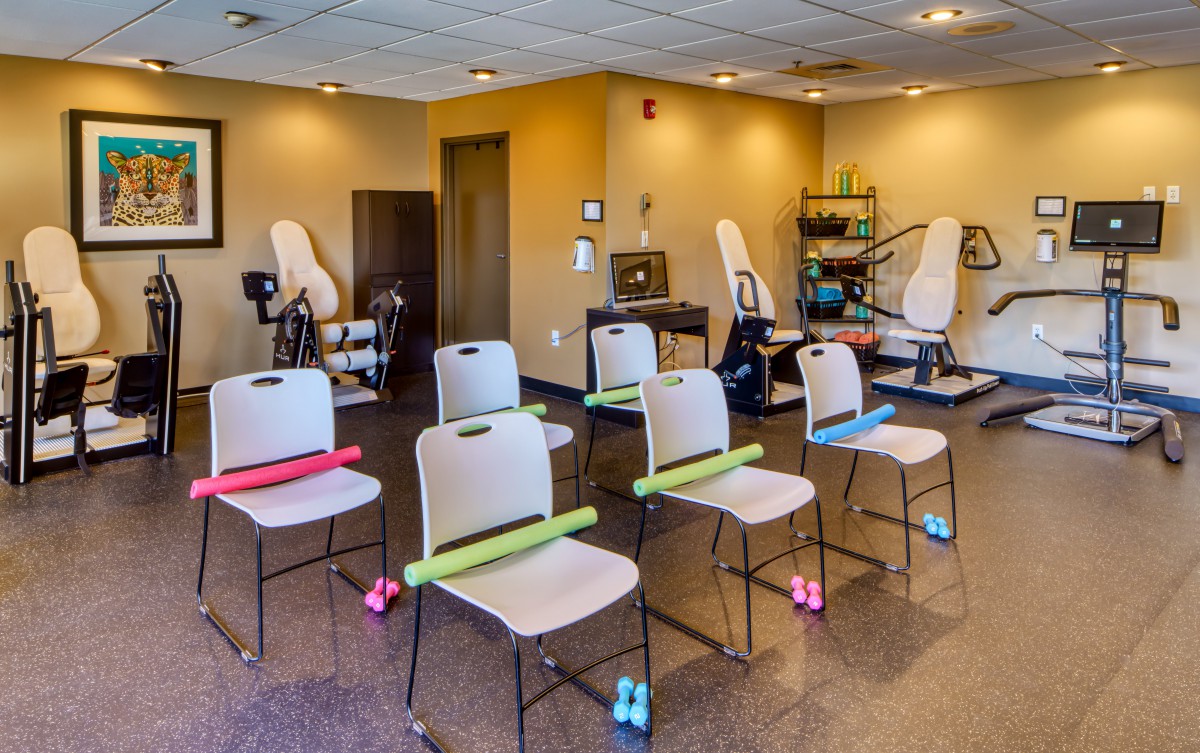 A fitness room with chairs set up for exercise, featuring foam rollers and dumbbells.