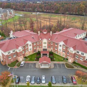 Aerial view of a large building surrounded by trees with a parking lot in front during autumn.