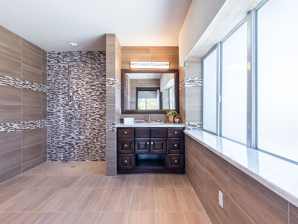 A modern bathroom with a stone feature wall, wooden flooring, and a sleek vanity.