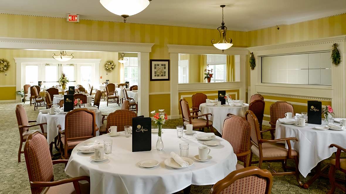 A warmly decorated dining room with neatly set tables and elegant lighting.