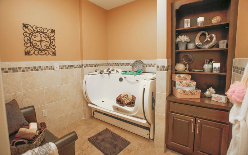 A stylish bathroom featuring a walk-in bathtub and decorative shelving.