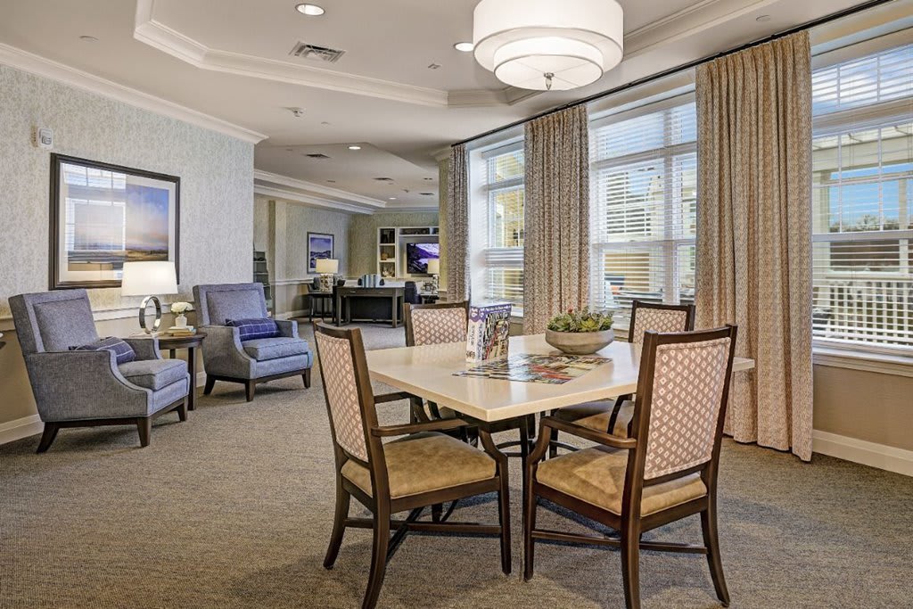 A well-furnished dining area with a table, chairs, and large windows.