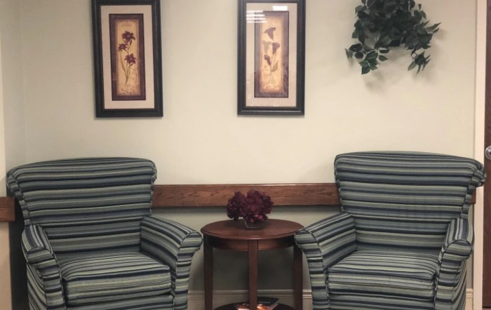 A waiting room with two striped chairs, a small table, and decorative wall art.