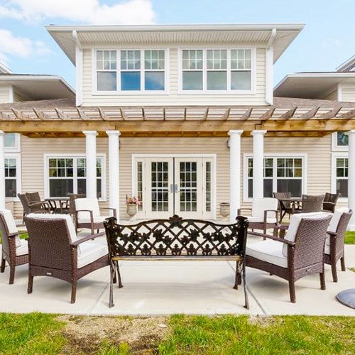 A spacious patio with outdoor furniture and a pergola attached to a residential house.
