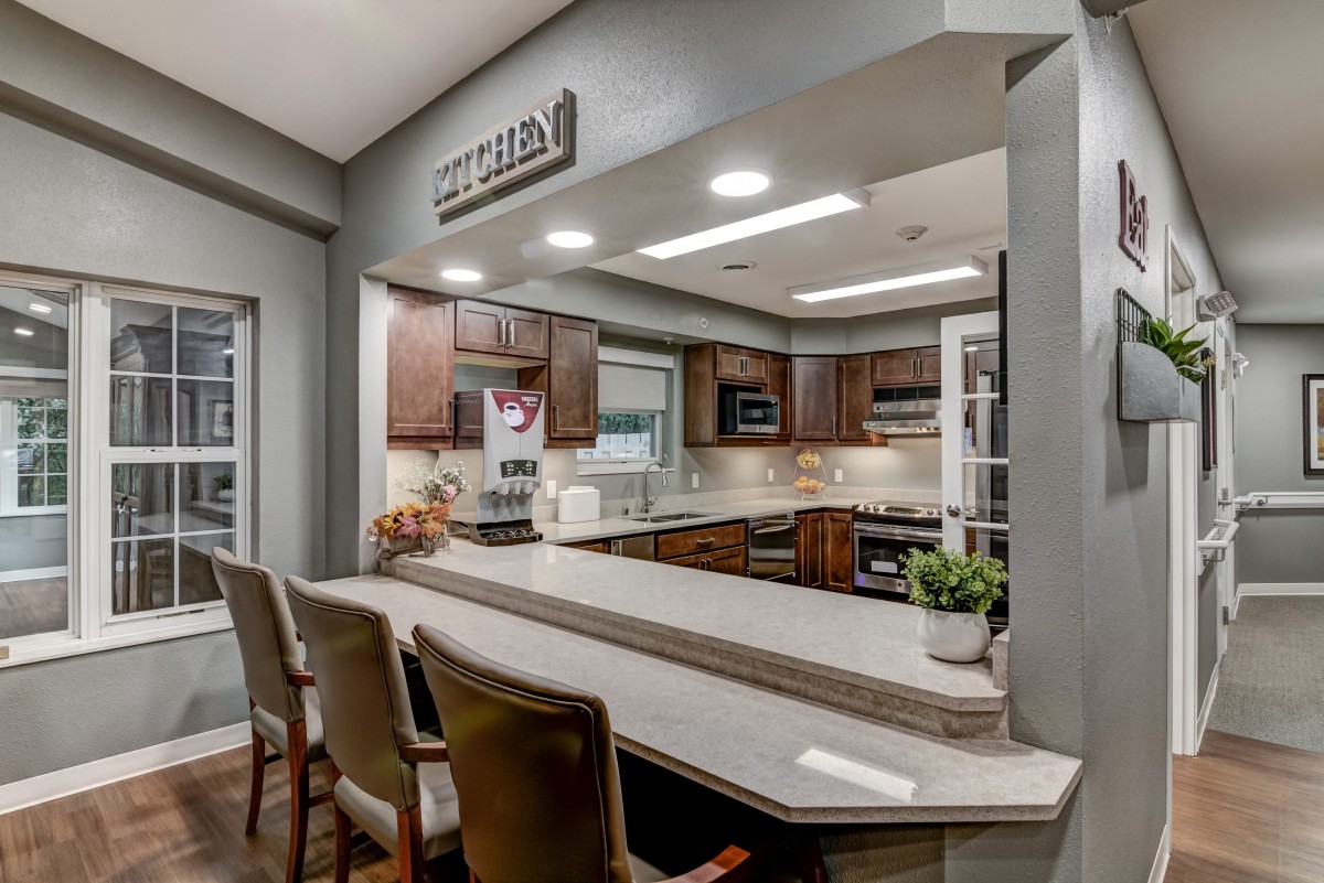 A modern kitchen with wooden cabinetry, a spacious countertop, and comfortable bar stools.