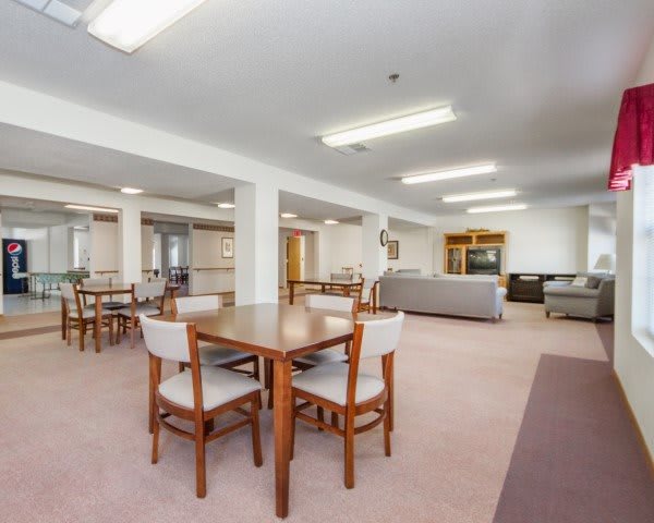 Spacious dining and sitting area with tables, chairs, and sofas under bright lighting.