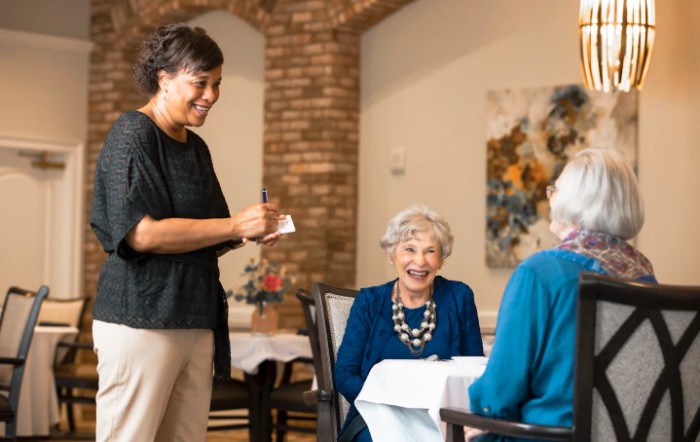 A waitress taking an order from two elderly women at a restaurant.