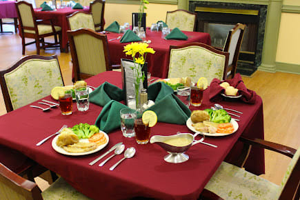 A formal dining table set with plates of food and neatly folded napkins.