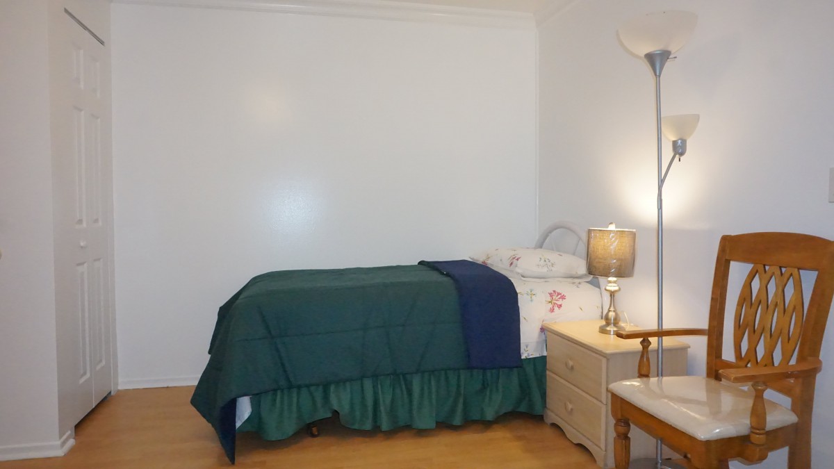 A minimalist bedroom with a single bed, nightstand, and lamp.