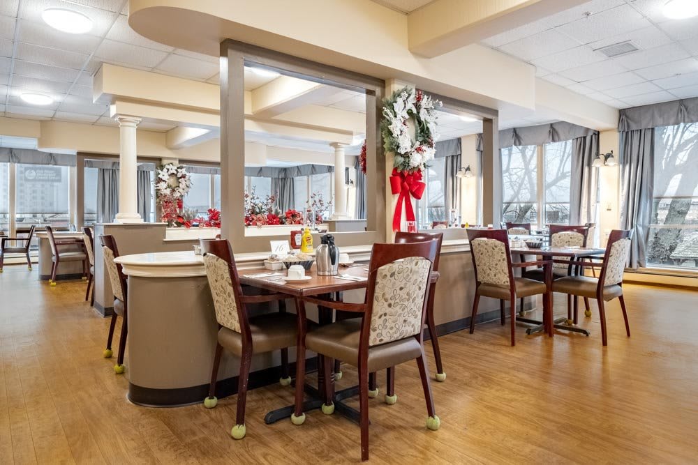 A cozy dining room decorated with festive holiday ornaments, featuring tables and chairs arranged neatly.
