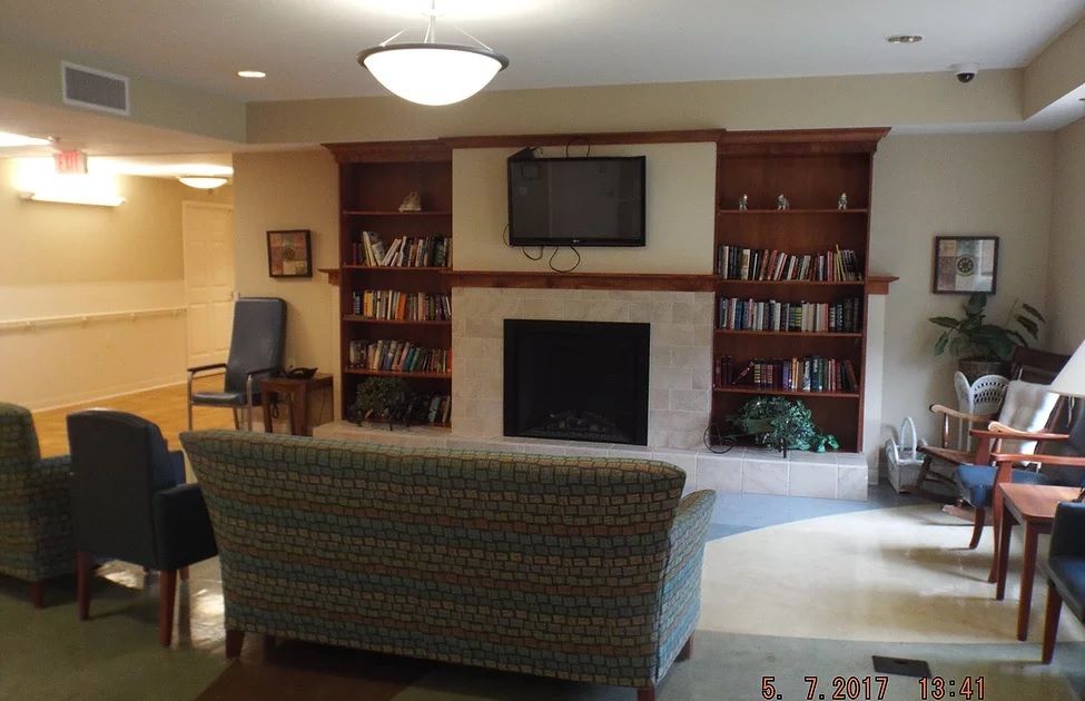 A cozy living room featuring a fireplace, television, and bookshelves, with a comfortable sofa for relaxation.