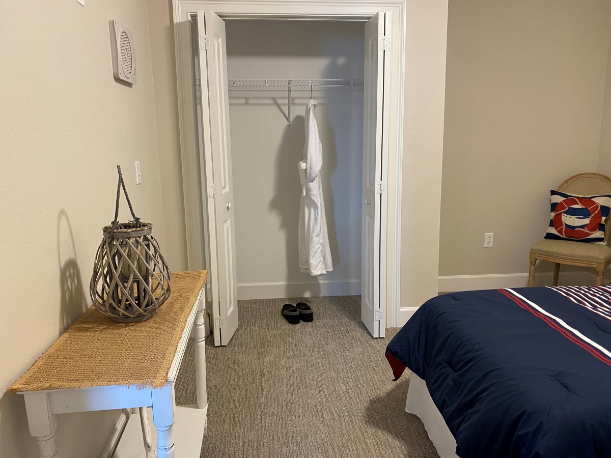 A minimalist bedroom featuring an open closet with a robe hanging inside.