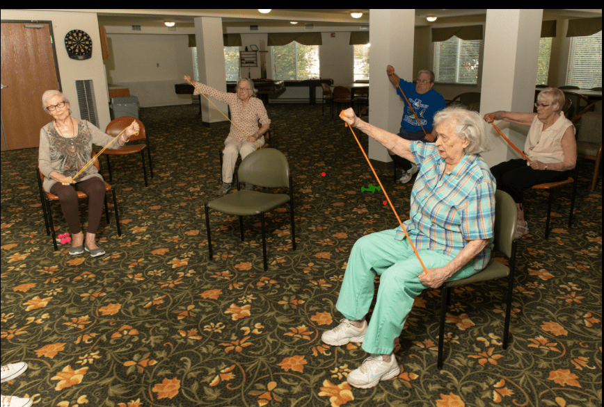 A group of seniors participating in a chair exercise class indoors.