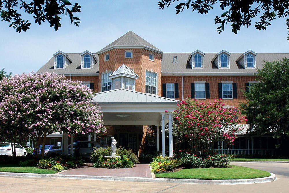 A view of a brick building with dormer windows and well-maintained landscaping.