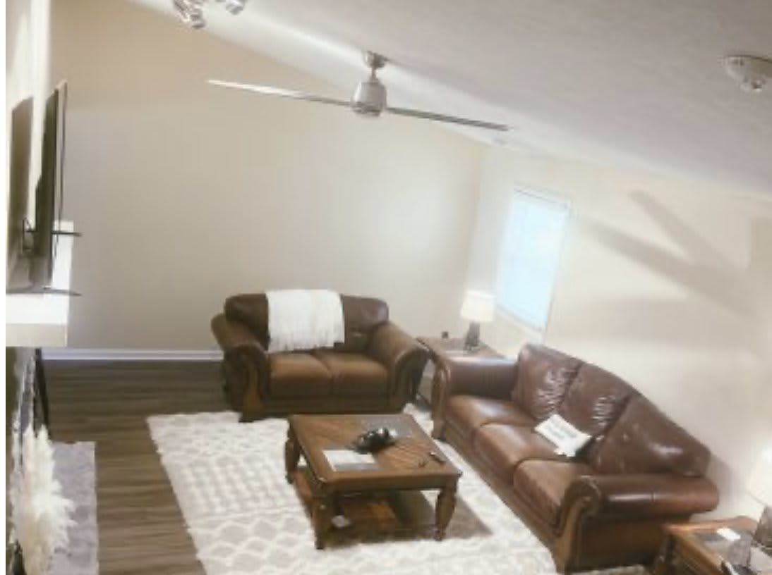Cozy living room with leather furniture and a ceiling fan.