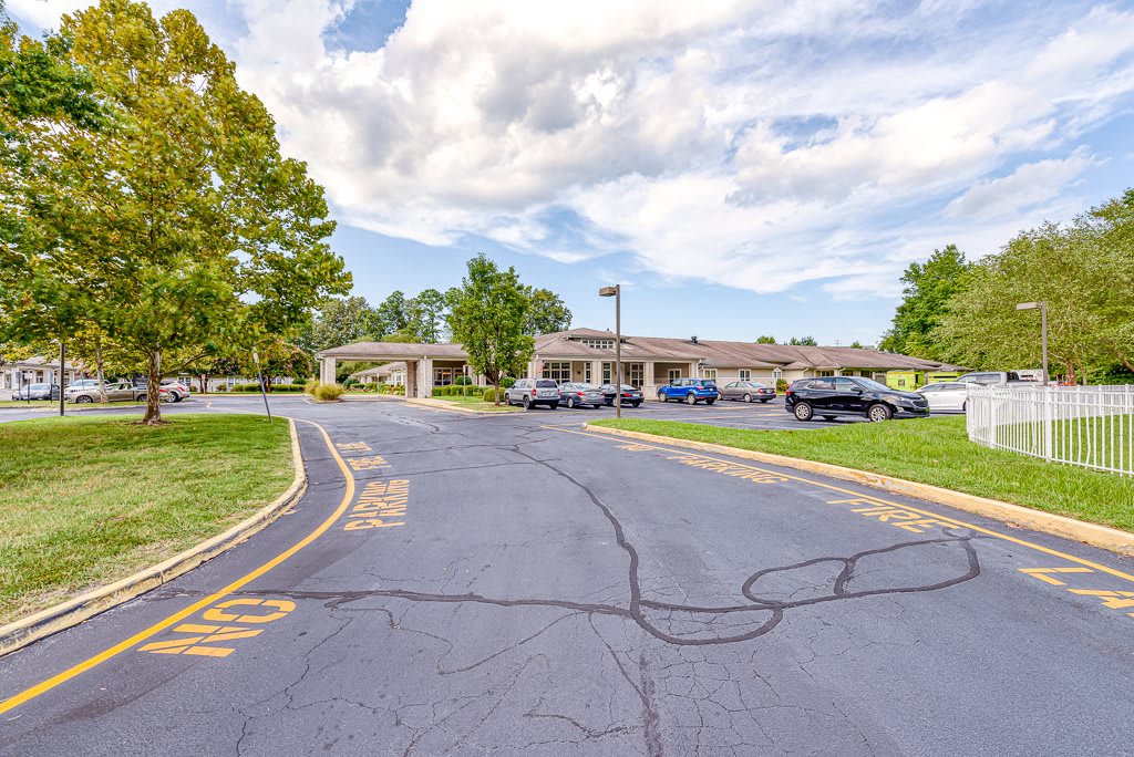 A view of a parking lot and building surrounded by trees under a cloudy sky.