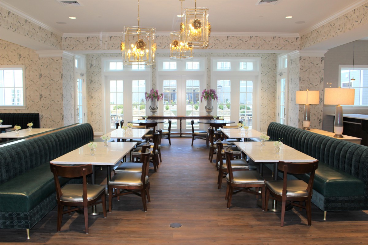 A modern dining area with elegant chandeliers, large windows, and neatly arranged tables and chairs.