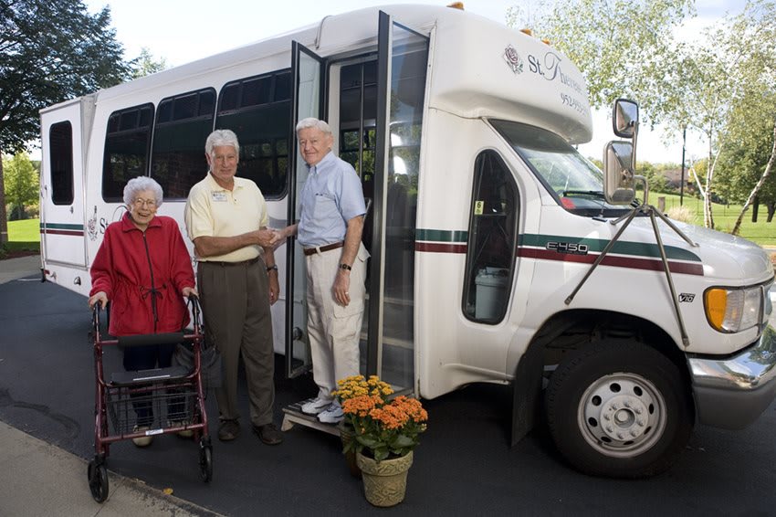 Elderly individuals standing next to a community transport bus.