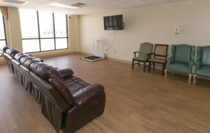 A spacious living area with a leather couch, chairs, and a wall-mounted television.