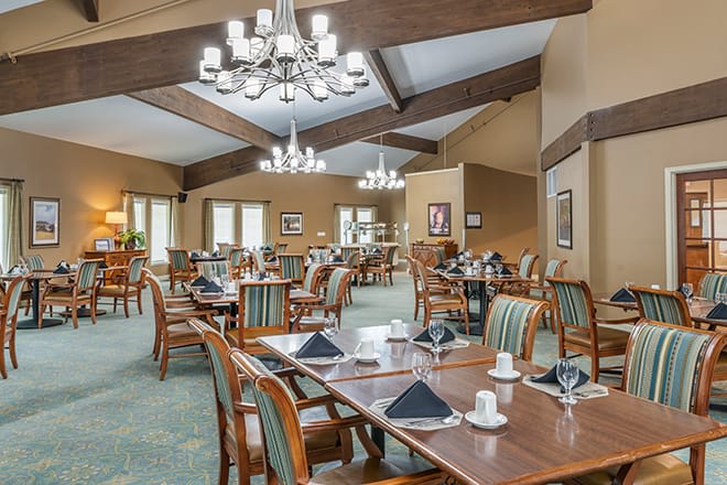 An elegant restaurant dining area with neatly arranged tables and chairs, accented by chandeliers.