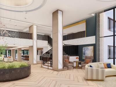 A spacious and modern hotel lobby featuring a central staircase, seating areas, and decorative plants.