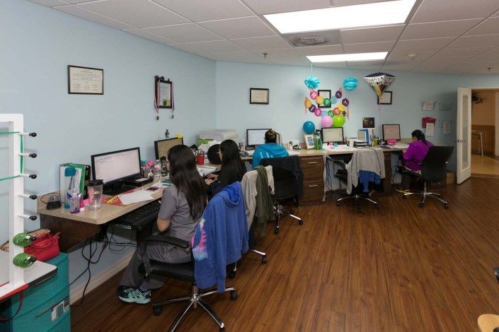 An office environment with several people working at desks with computers.
