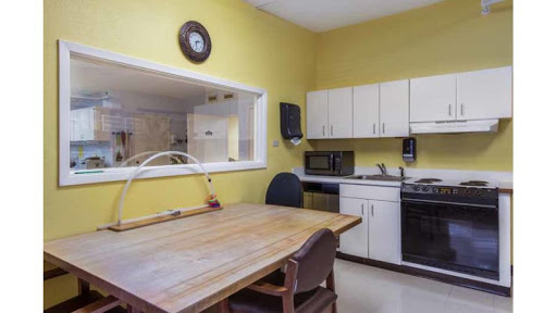 A cozy kitchen featuring yellow walls, a wooden dining table, and modern appliances.