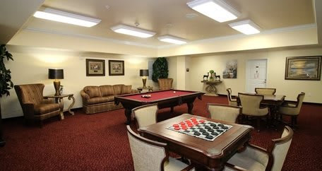 A cozy game room with a billiards table and checkers set, featuring comfortable seating and warm lighting.