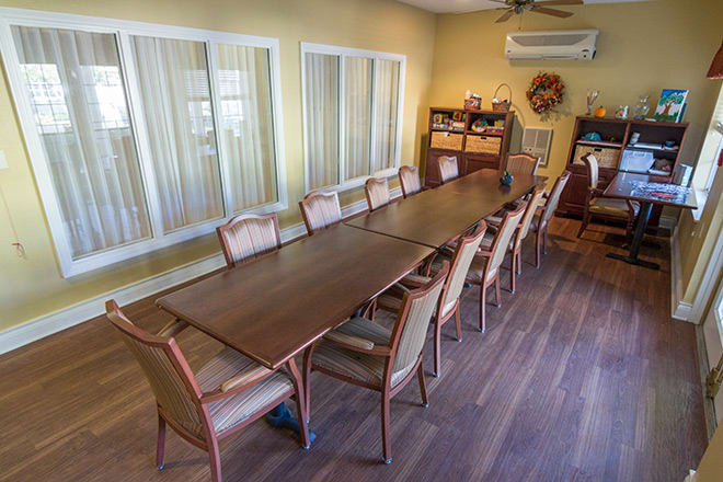 A spacious conference room with a long meeting table surrounded by several chairs.