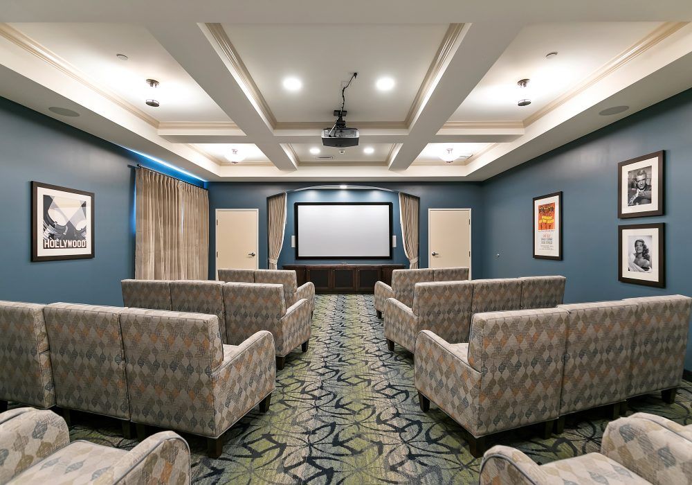 A modern home theater room with comfortable seating and a large projector screen.