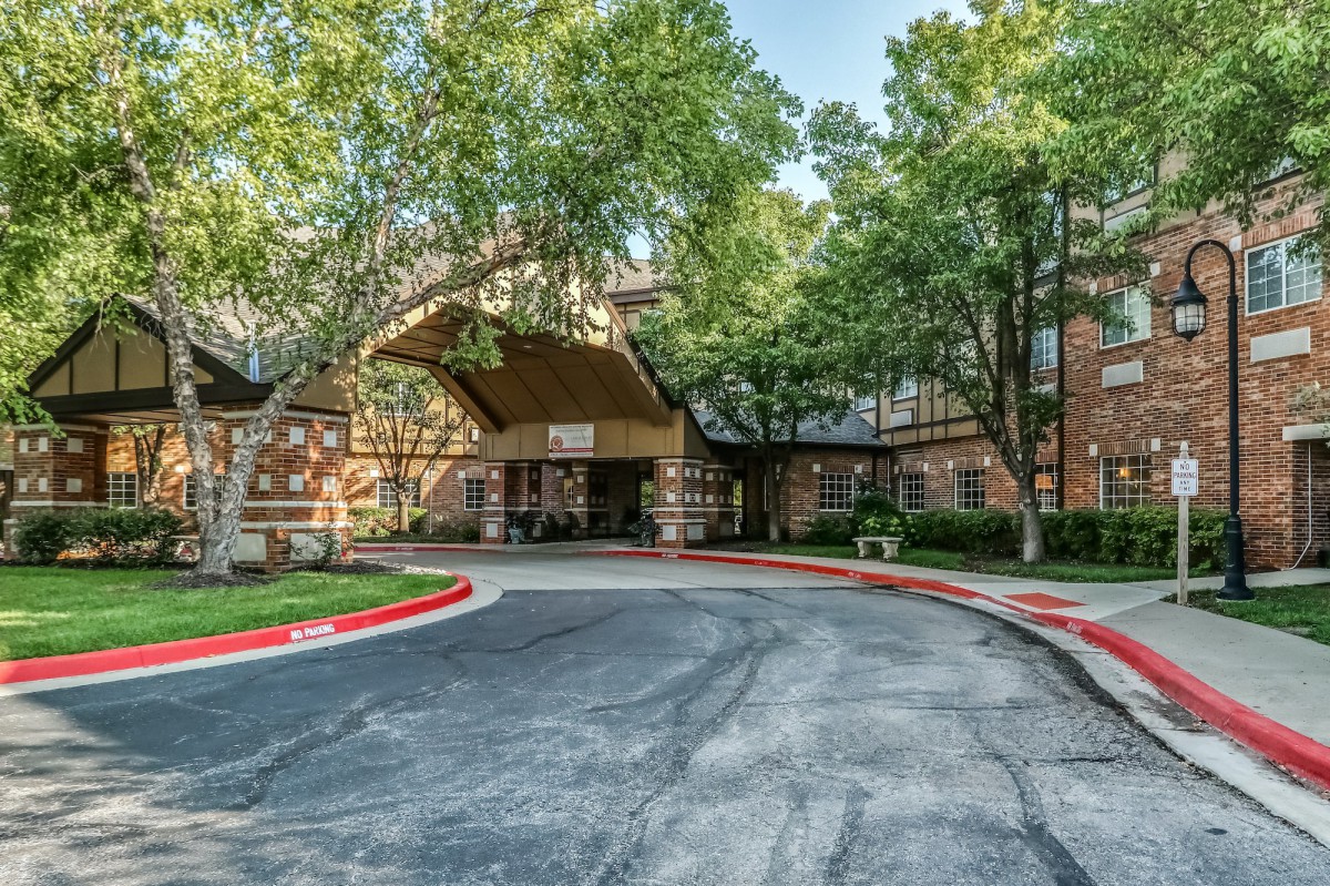 A welcoming building entrance surrounded by trees and a circular driveway.
