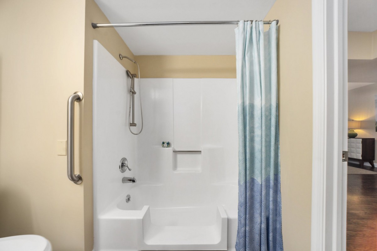 A modern bathroom featuring a bathtub with an overhead shower and a blue gradient curtain.