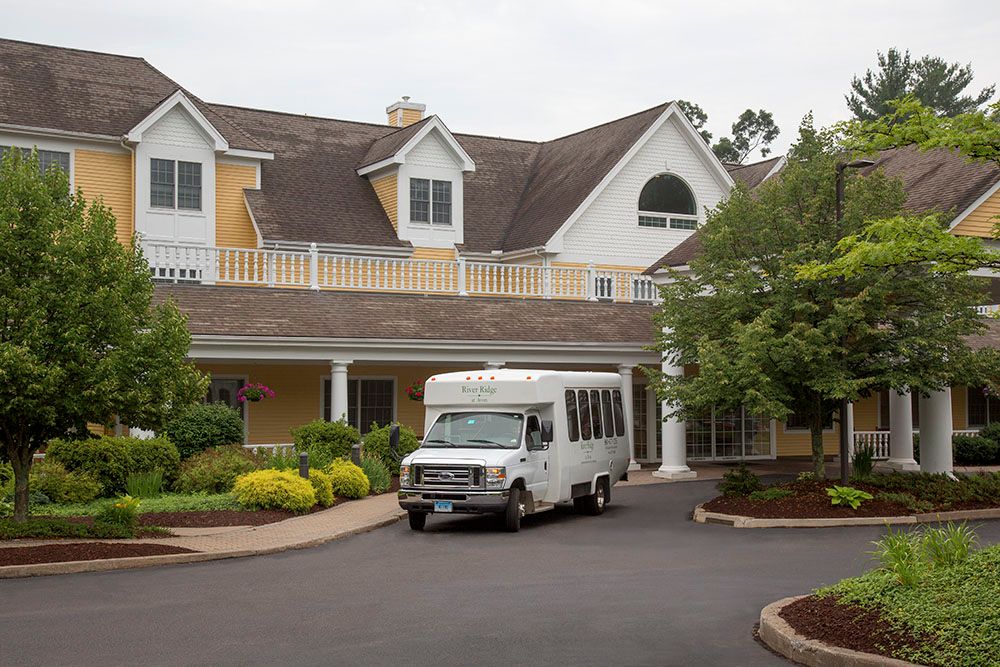 A van is parked in front of a large house with a landscaped driveway.