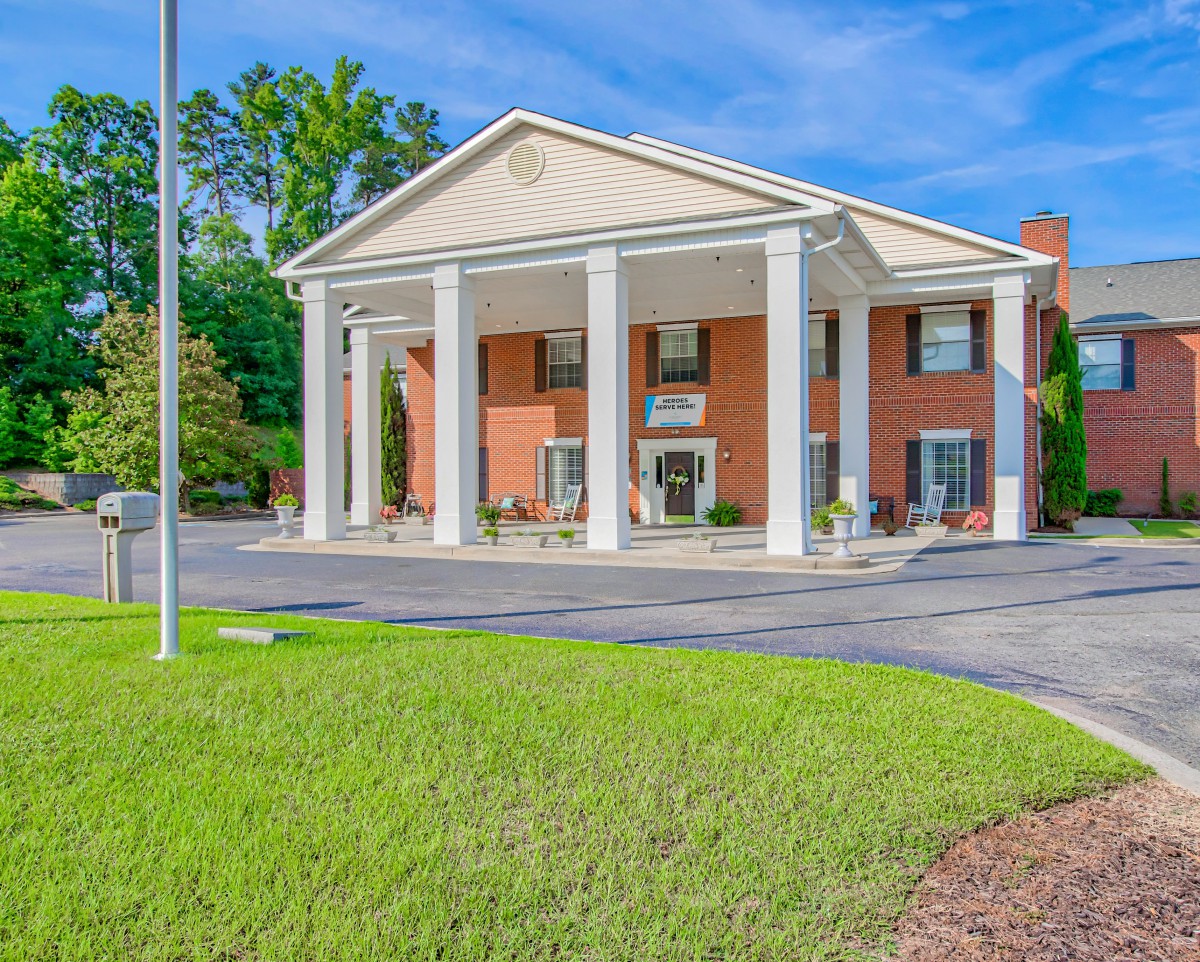 A brick building with large white columns under a clear blue sky.