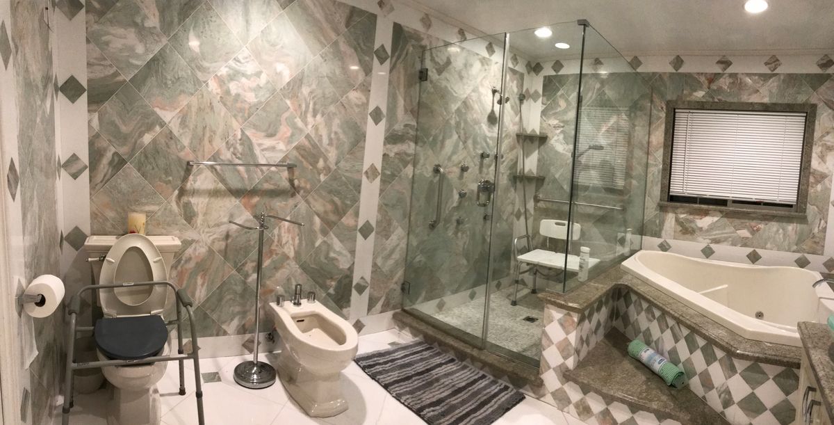 A luxurious bathroom featuring a marble design with a glass-enclosed shower and bidet.