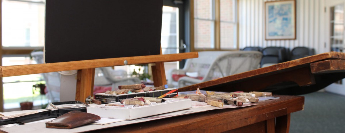 An artist's workstation featuring an easel with canvas and various painting supplies.