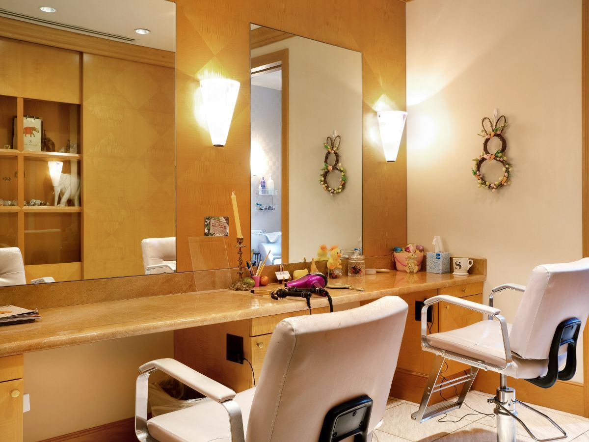 A stylish hair salon interior with comfortable chairs and a well-lit vanity area.