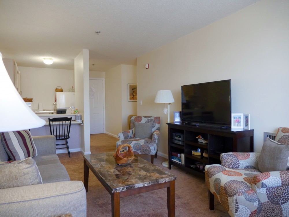 A cozy living room with a sofa, chairs, and a large television.