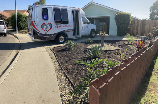 A specialized van parked in a driveway next to a well-maintained garden.