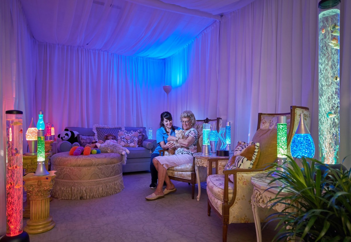 A cozy lounge area with soft lighting and comfortable seating, where children are enjoying their time surrounded by toys.